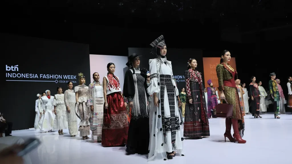 Model mengenakan busana ulos modern pada Indonesia Fashion Week 2026 dengan desain yang memadukan wastra Batak dan gaya fashion kontemporer.